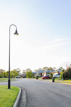 light lamp post and houses with evening light on homes and cars parked in driveways
