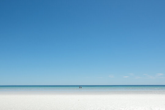 Two People Standing In The Water At The Beach