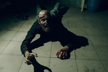 Zombie male crawl on floor halloween concept. Make up skin and blood face