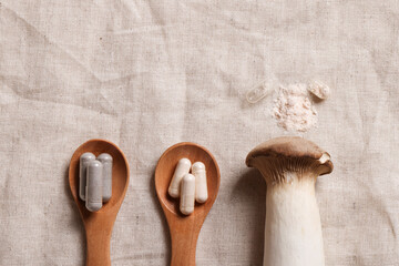 mushroom and natural herbal pills on wood spoons on textile background. environmental friendly ,...