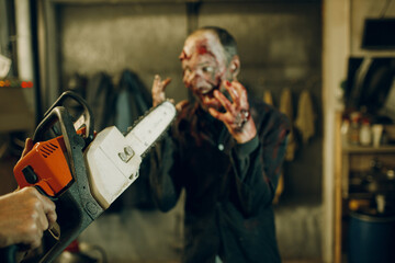 Fototapeta na wymiar Zombie and chainsaw defence halloween concept. Make up skin and blood face