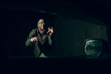 Obraz na płótnie Canvas Zombie male attack car driver through vehicle window glass halloween concept.