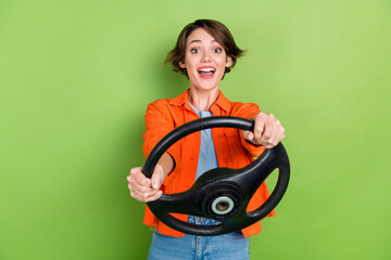 Photo of impressed funky lady dressed jeans shirt open mouth driving auto isolated green color...