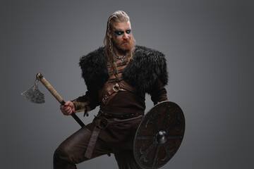 Fototapeta na wymiar Shot of ancient viking vandal dressed in armor and black fur against grey background.