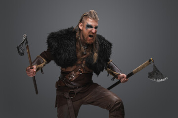 Portrait of crying viking with dual axes dressed in deerskin and armor.