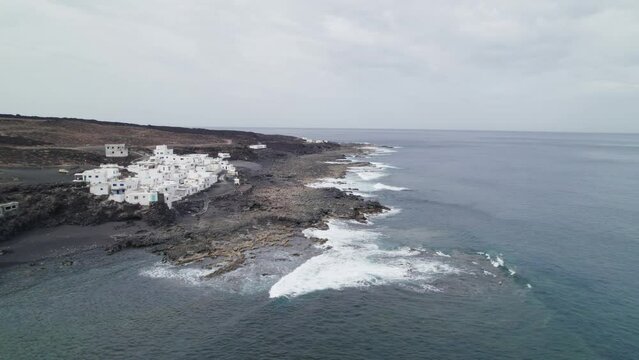 Flying to Tenesar village in Lanzarote, Canary Islands, waves crashing on rocks, white houses