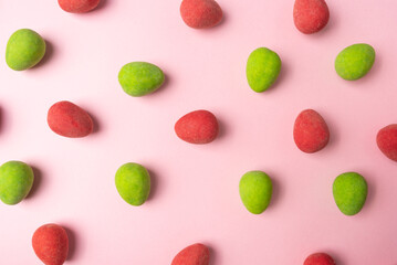 Background image with bright green and red candies on a pink colored surface.