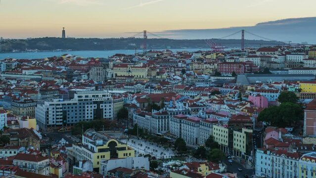 Day to night time-lapse of Lisbon famous view from Miradouro da Senhora do Monte tourist viewpoint over Alfama old city district, 25th of April Bridge. Lisbon, Portugal. Zoom out effect
