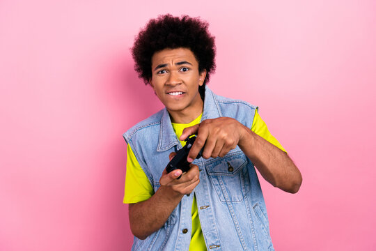 Portrait of addicted young gamer guy arms hold gamepad play games tryhard isolated on pink color background