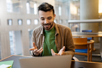 Handsome smiling latin man using laptop computer explaining something having video call. Successful...
