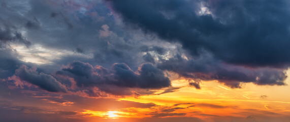 A sunset or sunrise sky with sun and rainy clouds as a background or texture