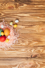 Colored eggs of different sizes on a brown wooden background. Symbol of the Easter holiday. Easter background, flat lay