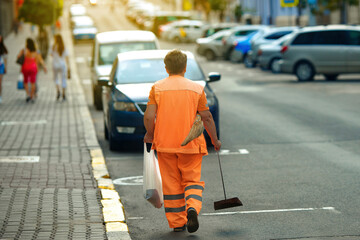 Female worker in orange uniform with broomstick and scoop for garbage sweep street. Municipal...