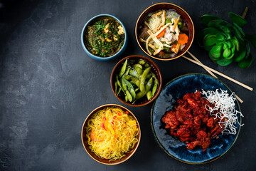 Asian traditional food rice noodles with red pepper, sweet and sour chicken, chicken noodle soup with mushrooms, beans, homemade cheese with spinach and spices.