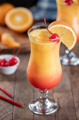 Tequila sunrise cocktail garnished with cherry and orange slice - 579039699