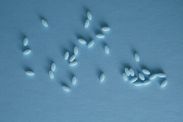 Pharmaceutical nutraceutical medicine blue tablets spilled on blue background