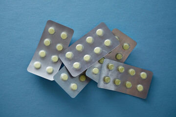 Pharmaceutical different colors tablets in medication blister packs closeup on blue background