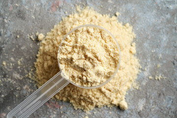 Vanilla whey protein powder in a measuring spoon