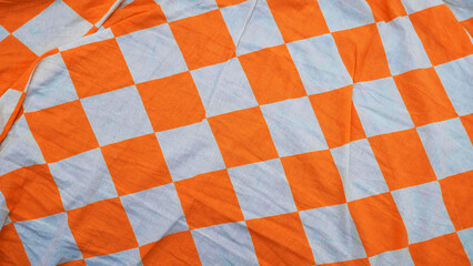 Orange and white checkered fabric. The texture of cloth. Crumpled fabric. Background 