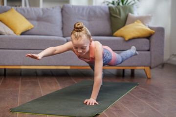 Little girl practicing stretching in room. Physical exercises for children at home. Concept of sport