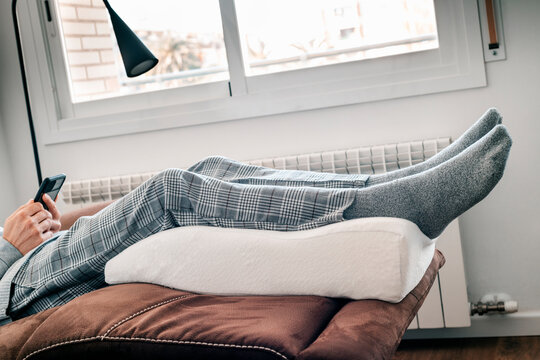 man leaning his legs on an elevation pillow