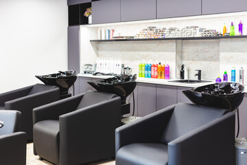 Beauty salon barbershop interior. Large comfortable black leather armchairs in a modern, cozy and bright room.