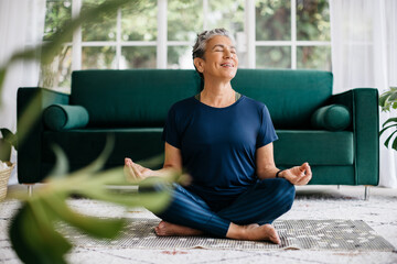Meditation in lotus position: Mature woman practicing yoga at home