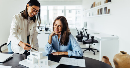 Two female architects discussing a 3D model in an office