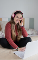 smiling girl with computer on the bed, listening to music