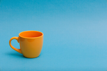 Yellow cup on a blue background with negative space for text.