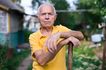 Portrait of an elderly man with shovel in garden