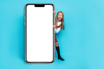 Full body portrait of funny schoolchild big empty space telephone ui menu display isolated on blue color background