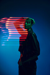 Half-length portrait of young stylish woman posing over dark blue background with neon mixed light lines. Concept of contemporary art, fashion, cyberpunk, futurism - obrazy, fototapety, plakaty