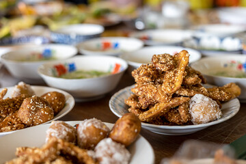Many delicious fried banana snacks packed in plates placed amongst other Thai desserts.