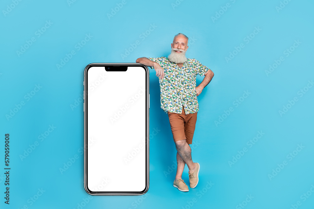 Wall mural Full size portrait of handsome positive person stand near huge empty space telephone display isolated on blue color background