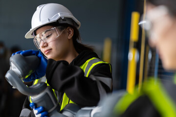 Fototapeta premium A team of female engineers meeting to inspect computer-controlled steel welding robots. Plan for rehearsals and installation for use.