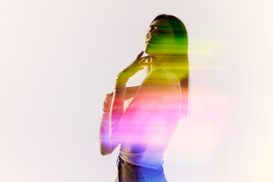 Surreal portrait of young adorable woman posing over white background with mixed neon colored light on her body. Concept of contemporary art, fashion, futurism