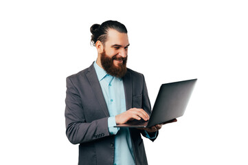 Portrait of a handsome man wearing a jacket and typing on the laptop he holds.