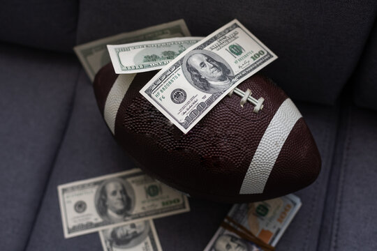 Football ball and money on gray background