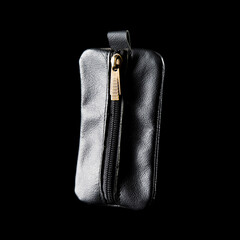 A simple black leather keychain pouch, isolated on black background