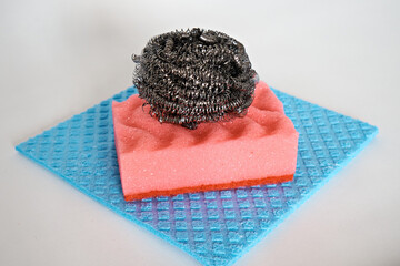 Demonstration of kitchen care products: a foam kitchen sponge and a metal sponge lie on an...