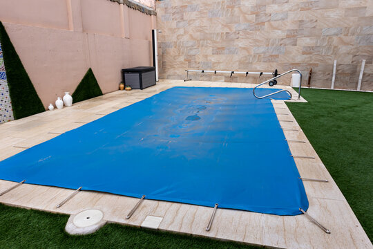 Small pool covered with a blue tarpaulin during the winter season to cover it and prevent dirt.