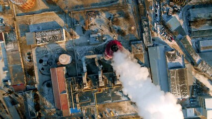 Aerial drone vertical view of thermal power plant in Chisinau, Moldova. View of a pipe with felling steam, bare trees, infrastructure around - Powered by Adobe