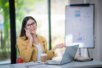 Happy businesswoman talking on mobile phone while analyzing weekly schedule in the office.