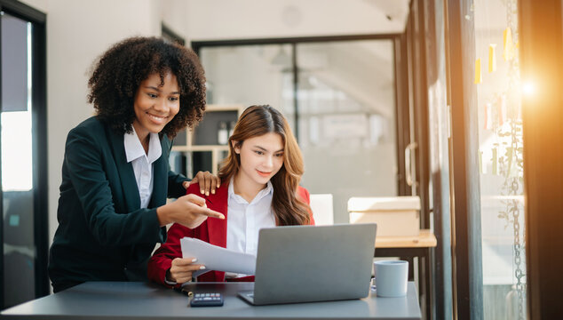 Two business workers talking on the smartphone and using laptop at the office..