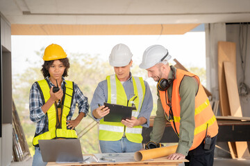 Architect colleagues mixed race working as a team discussing data working and tablet, laptop with on on architectural project at construction site at desk.