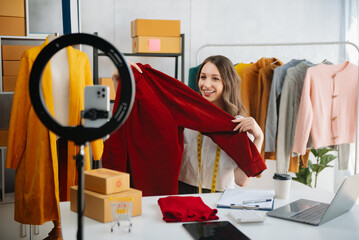 Beautiful lady blogger showing clothes in front of the camera to recording vlog video live...