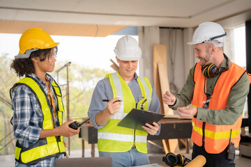 Architect colleagues mixed race working as a team discussing data working and tablet, laptop with on on architectural project at construction site at desk.