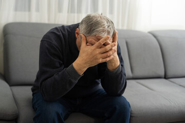 Elderly man with hand on his temple has a headache