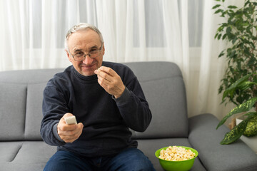 Senior gentleman sitting on a sofa and watching TV.